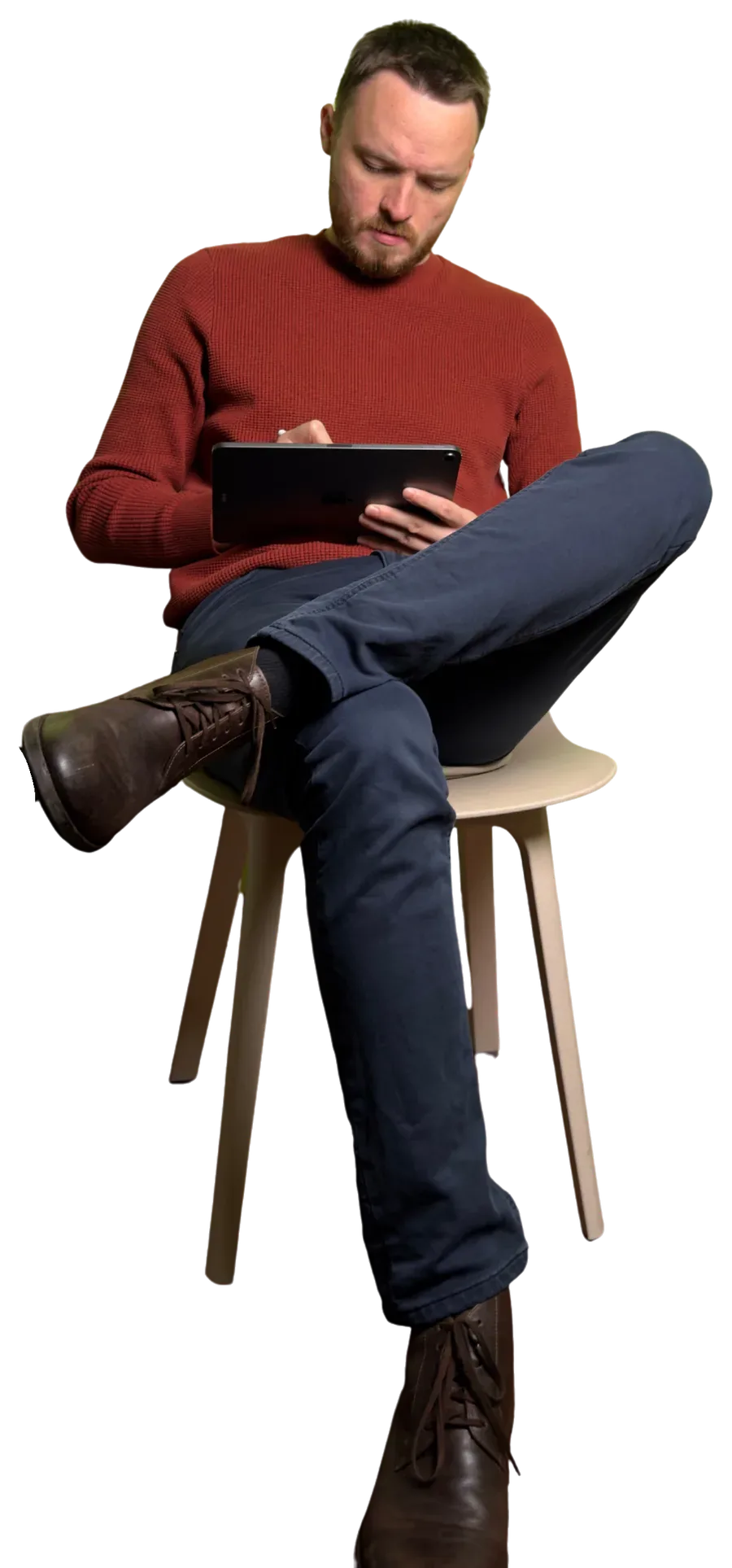 Anthony sitting on a bar stool, legs crossed, reading on a tablet