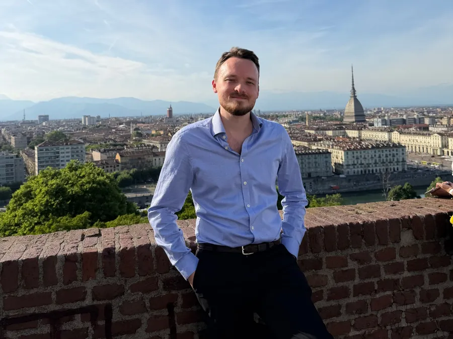 Anthony in a blue shirt, leaning on a brick wall above the rooftops of Turin