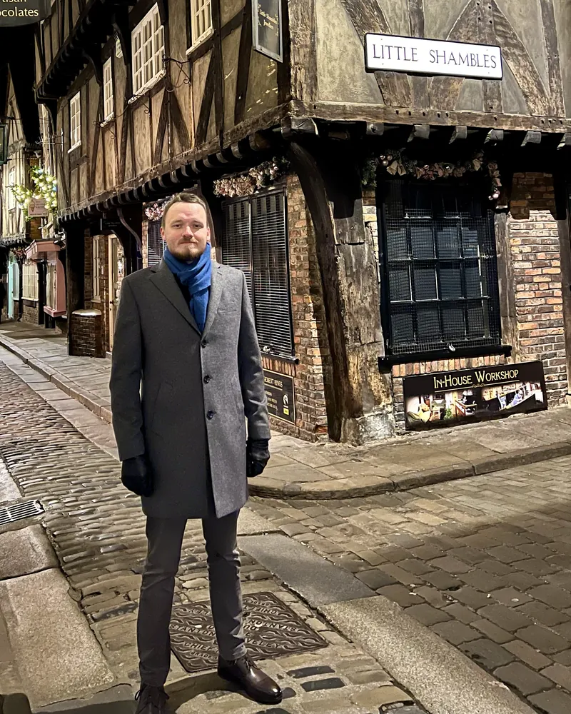 Anthony in a winter coat on the Shambles, a medieval street of timber-framed buildings in York
