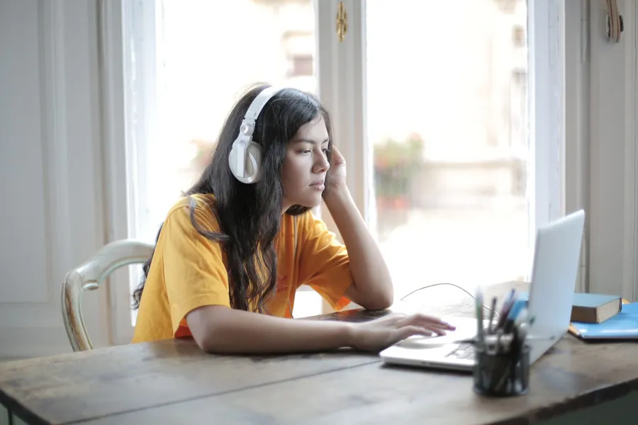 A student with headphones doing a listening practice test on her laptop