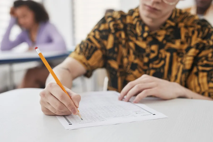 A student filling in an exam answer sheet with a pencil